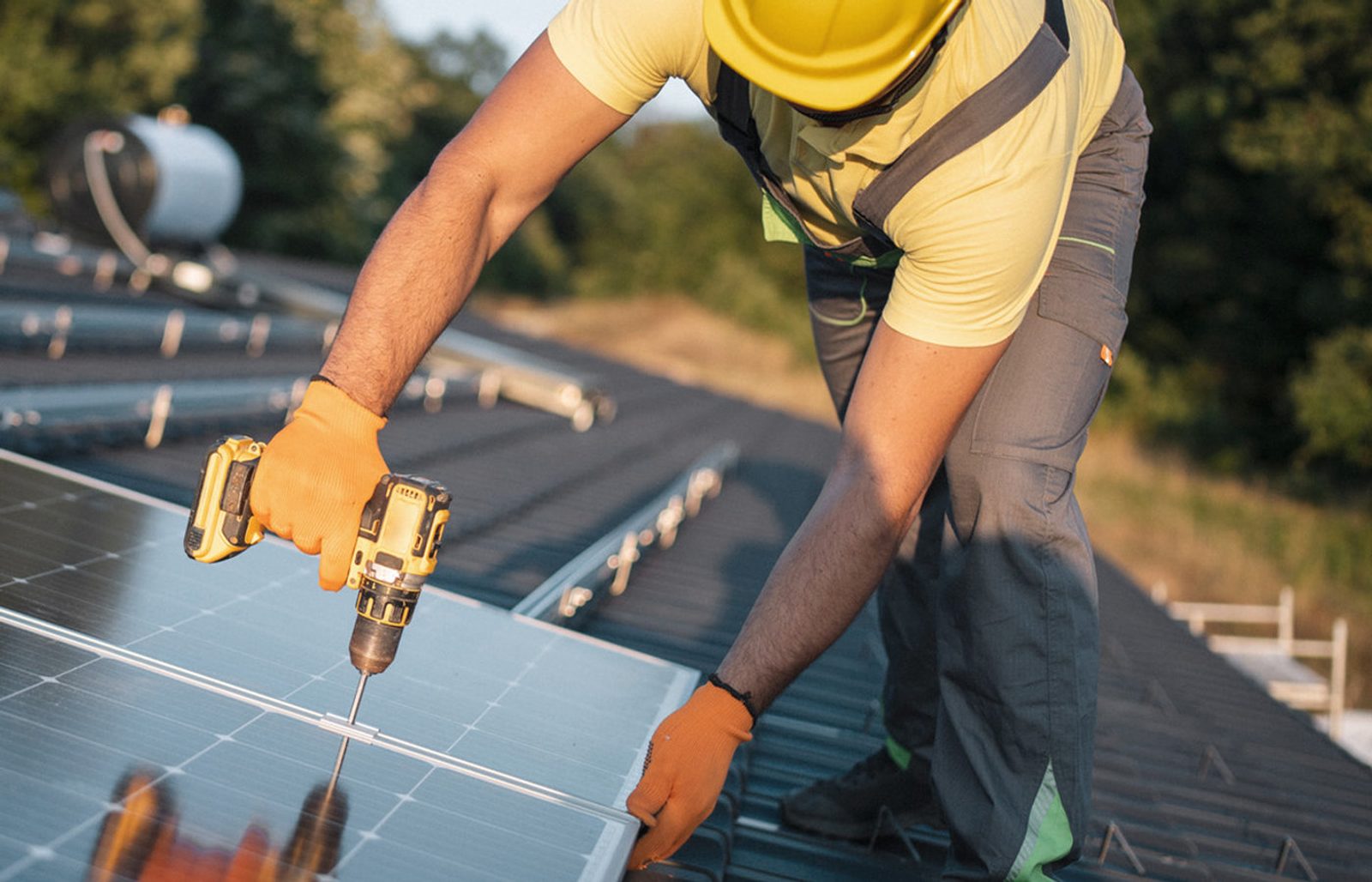 Installer securing a solar panel to roof rails