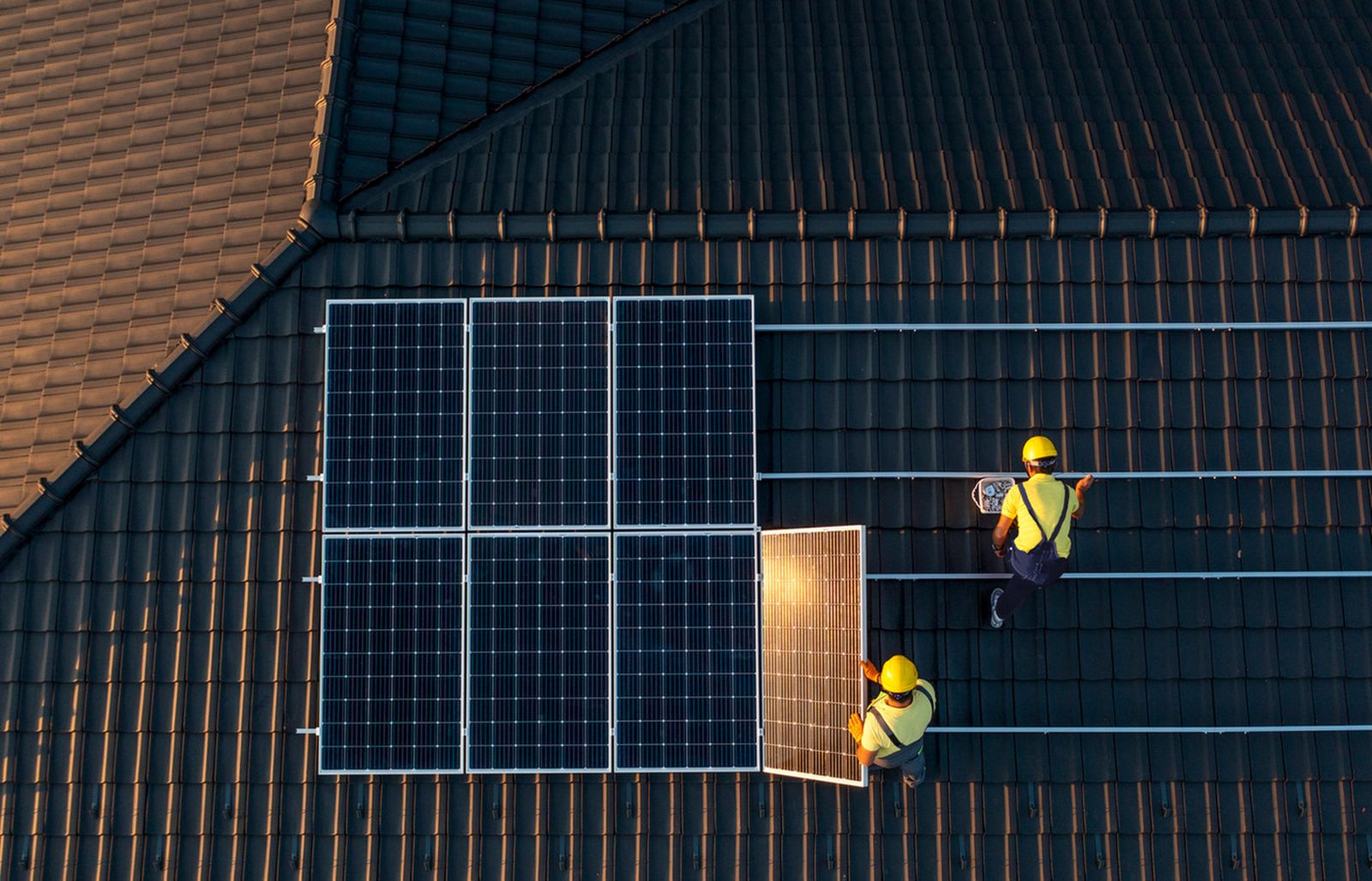 Installers fitting a solar array on a tiled roof