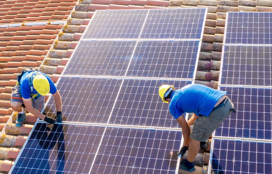 Two installers fitting panels to a tiled roof